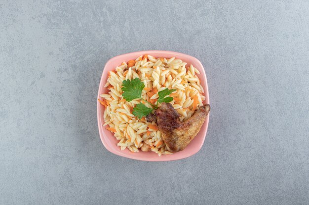 Delicious rice with grilled wing in pink bowl.