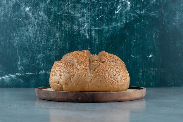 Delicious rye bun on wooden plate.