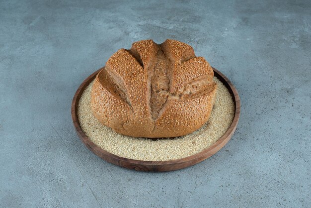 Delicious rye bun on wooden plate.