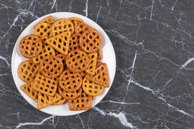 Delicious salty crackers on white plate.