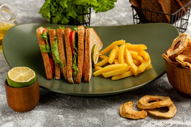 delicious sandwich with green salad tomatoes and ham inside plate with french fries