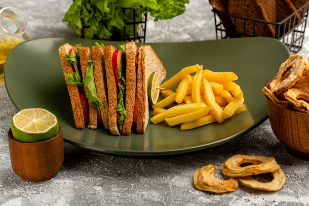 вкусный бутерброд с зеленым салатом, помидорами и ветчиной внутри тарелки с картофелем фри