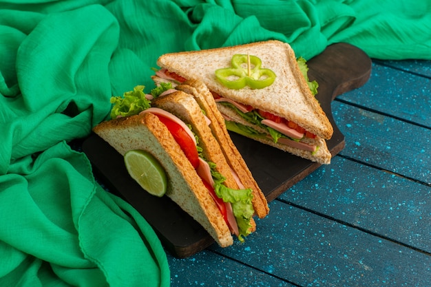 Free photo delicious sandwiches along with green tissue on blue