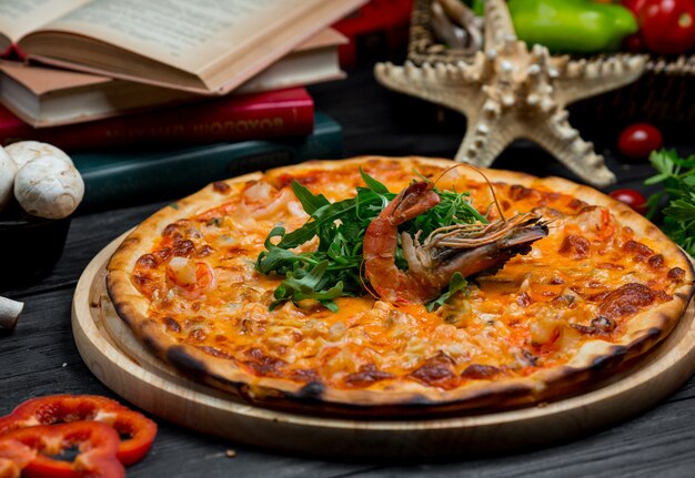 Вкусная пицца из морепродуктов с плавленым сыром, жареным крабом и зеленым салатом на вершине