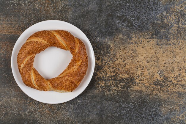 Delicious simit with sesame seeds on white plate