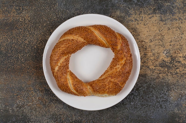 Delicious simit with sesame seeds on white plate. 