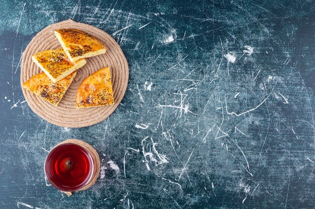 Delicious sliced pastry with seeds and glass of fresh juice on marble background. 