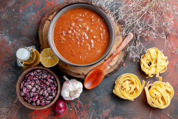 Delicious soup for dinner with a spoon and lemon on a wooden tray beans garlic onion and other products on mixed color table