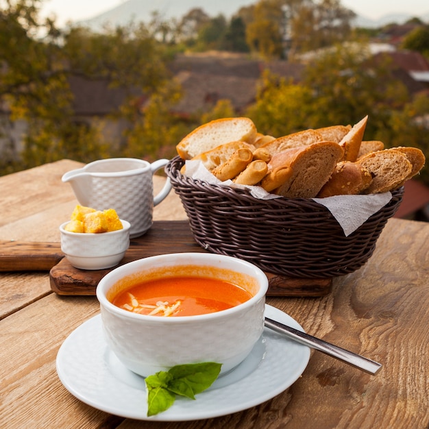 背景の森とパン高角度のビューとボウルにおいしいスープの食事