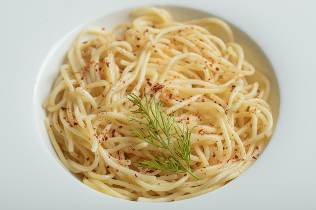 Free photo delicious spaghetti with greens on a white plate.