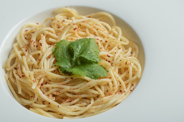 Вкусные спагетти с зеленью на белой тарелке.