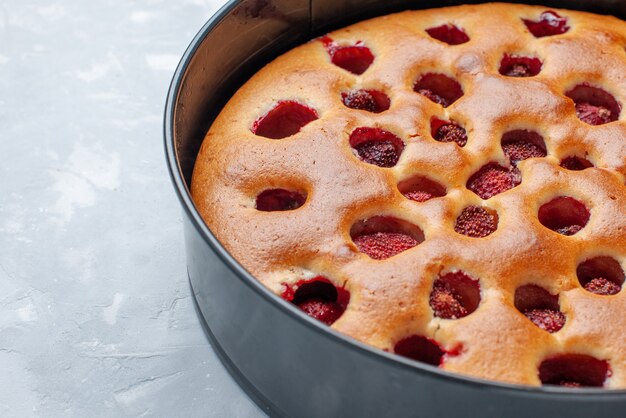 delicious strawberry cake baked with fresh red strawberries inside with pan on light , cake biscuit fruit sweet dough bake