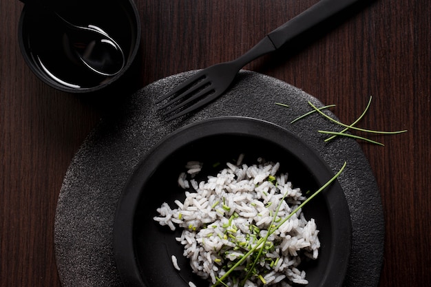 Вкусный рис для суши на черной тарелке с вилкой и соевым соусом