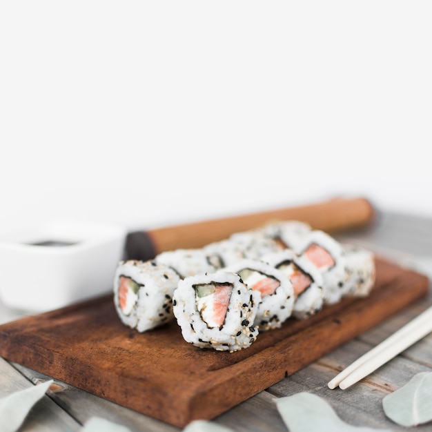 Delicious sushi roll with sesame seeds arranged on wooden tray