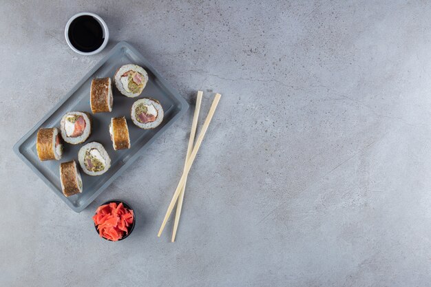 Вкусные суши-роллы с тунцом на темной тарелке.