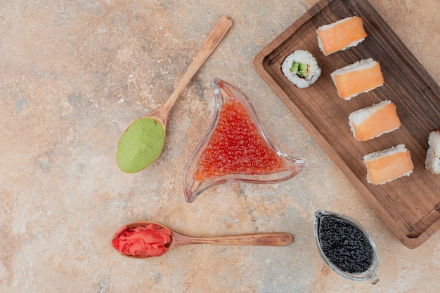 Delicious sushi with caviar, ginger and vasabi on wooden plate .