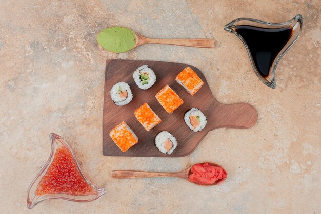 Delicious sushi with caviar, ginger and vasabi on wooden plate .