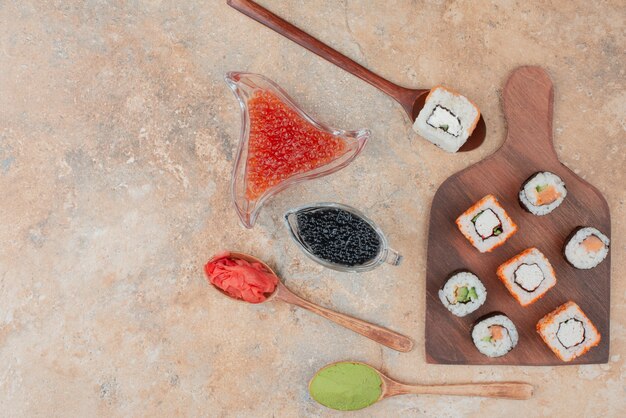 Delicious sushi with caviar, ginger and vasabi on wooden plate .