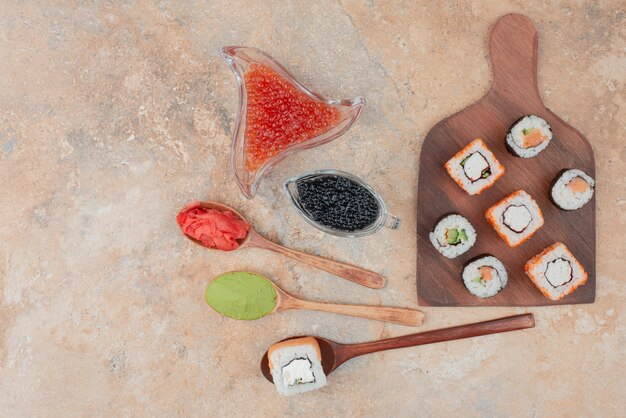 Delicious sushi with caviar, ginger and vasabi on wooden plate .