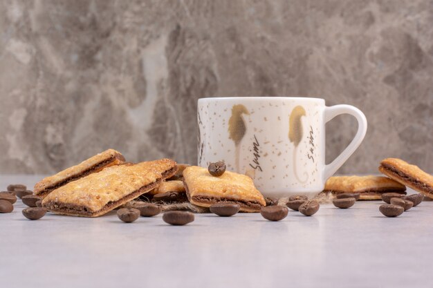 Delicious sweet crackers with white cup of coffee on sackcloth. High quality photo