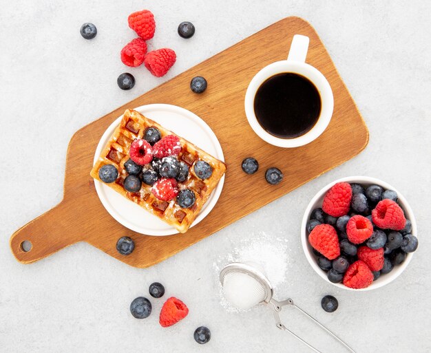 Delicious sweet waffles and coffee on wooden board