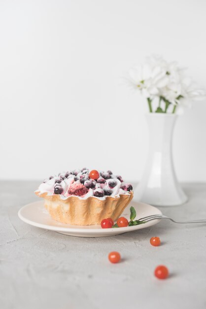 Delicious tart with blueberries on ceramic plate against white backdrop