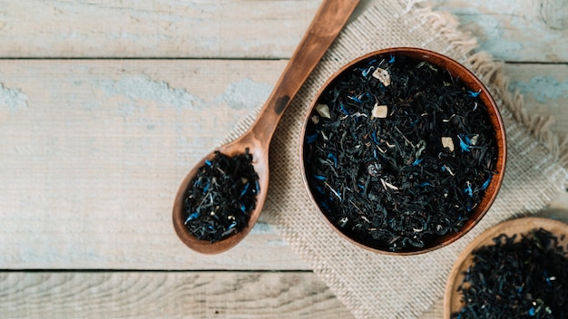 Delicious tea herbs in bowl on a wooden background