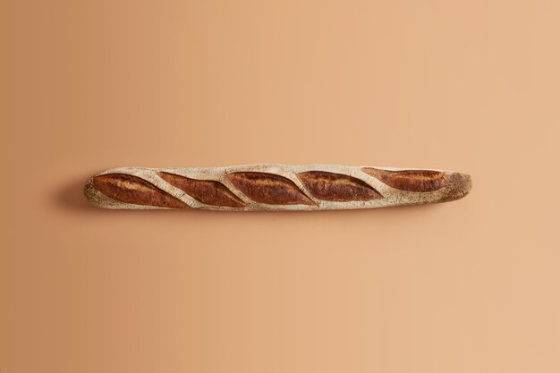 Delicious traditional french crusty baguette baked by professional, ready to be consumed, isolated on beige background. Organic sourdough product. Home cooking, bakery, natural food concept.