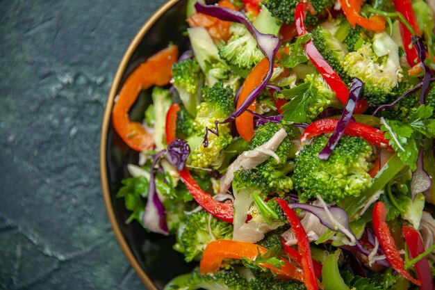 вкусный веганский салат в тарелке с различными свежими овощами на темном фоне