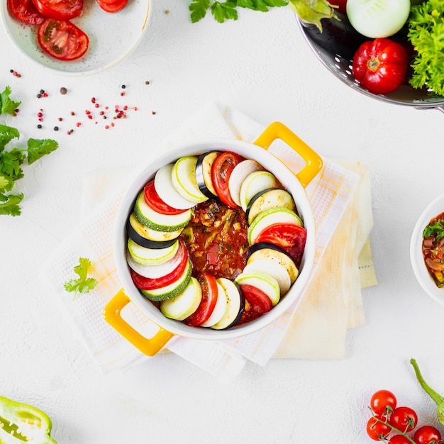 Delicious vegetable ratatouille in a white baking dish on a wooden background