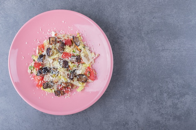 Delicious vegetable salad on pink plate.