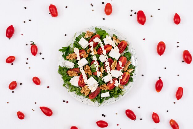 delicious vegetable salad with mayonnaise and walnut arounded by red cherry tomatoes and pepper powder