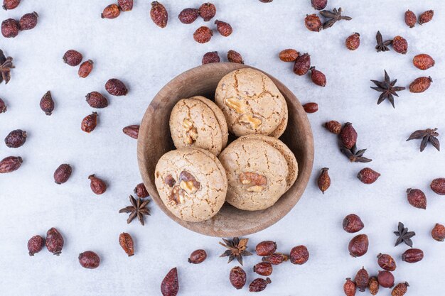 Delicious walnut cookies in bowl with rosehips.