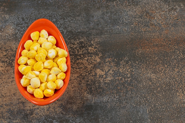 Delicious yellow candies in orange bowl.