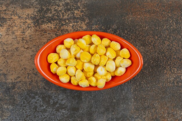 오렌지 그릇에 맛있는 노란색 사탕.
