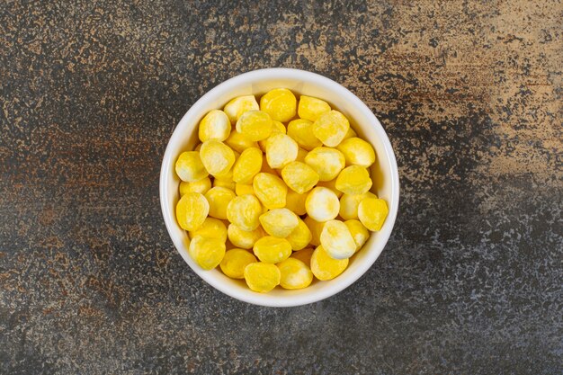 Delicious yellow candies in white bowl. 