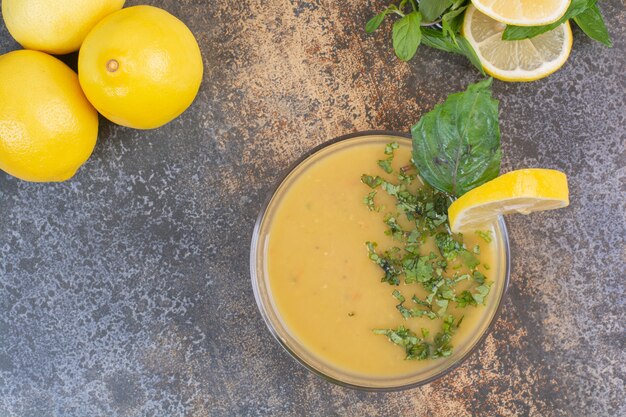 Delicious yellow soup with greens and lemons on glass plate