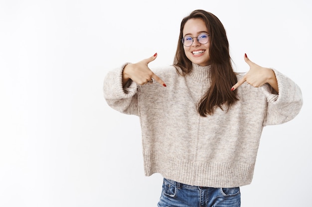 Delighted charismatic happy woman in glasses pointing at herself