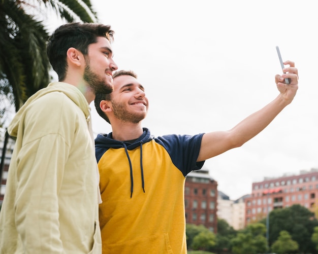 Delighted gay couple shooting selfie on street