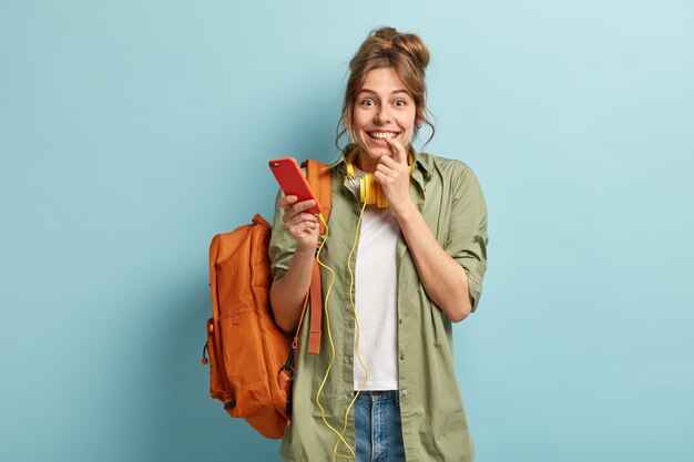 Delighted pleased woman listens audio in electronic headphones, feels good during online communication, has time for listening favourite music