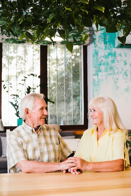 Delighted senior couple sitting in cafe and holding hands