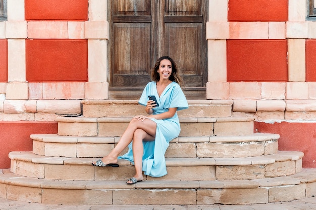 Foto gratuita smartphone di navigazione felice della donna vicino al beacon