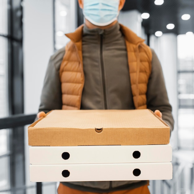 Free photo deliver man with mask holding package close up