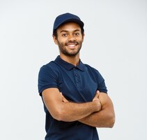 Free photo delivery concept - handsome african american delivery man crossed arms over isolated on grey studio background. copy space.