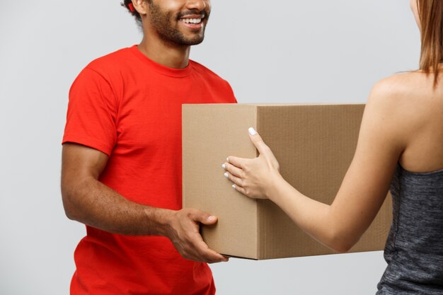 Delivery Concept - Handsome African American delivery man giving  package to homeowner. Isolated on Grey studio Background. Copy Space.