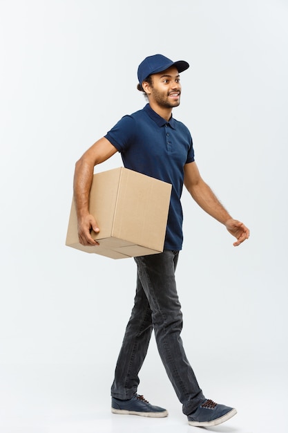 Delivery Concept - Handsome African American delivery man. Isolated on Grey studio Background. Copy Space.