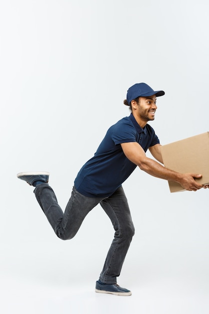 Delivery Concept - Handsome African American delivery man rush running for delivering a package for customer. Isolated on Grey studio Background. Copy Space.