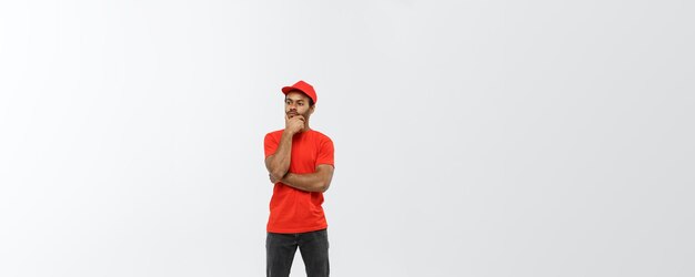 Delivery Concept Handsome African American delivery man serious thinking of something Isolated on Grey studio Background Copy Space