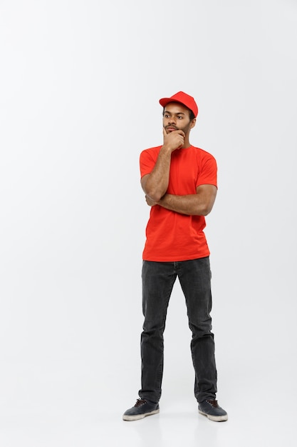 Delivery Concept - Handsome African American delivery man serious thinking of something. Isolated on Grey studio Background. Copy Space.