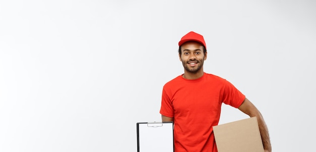 Free photo delivery concept portrait of handsome african american delivery man or courier showing a confirmation document form to sign isolated on grey studio background copy space